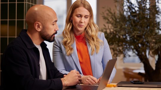 Man and woman working together collaborating using laptop