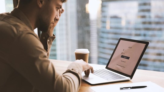 Thoughtful young man worker, student sit by laptop, prepare to input personal data entering account. Pensive millennial guy creating strong login password to electronic bank. Close up